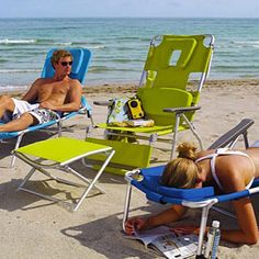 two people lounging in lawn chairs on the beach