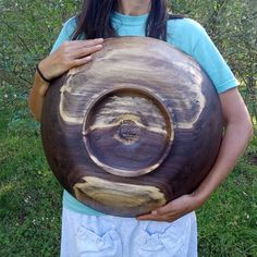 a woman holding a large wooden bowl in her hands