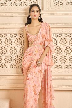 Peach pre-stitched saree with all-over floral prints and ruffle palla. Comes with printed, padded and embellished blouse. Paired with an embellished belt.
Components: 3
Pattern: Printed, Embellished
Type Of Work: Floral Patterns
Neckline: Scoop
Sleeve Type: Sleeveless
Fabric: Saree: Chiffon, Blouse: Georgette
Color: Peach
Other Details: 
Scalloped hem blouse
Ruffled saree
Blouse closure: Side zipper
Occasion: Destination Wedding - Aza Fashions Semi-stitched Georgette Blouse Piece With Ruffles, Summer Semi-stitched Pre-draped Saree For Designer Wear, Diwali Georgette Blouse Piece With Ruffles, Sleeveless Georgette Saree For Navratri, Designer Ruffle Saree For Navratri, Sleeveless Anarkali Style Pre-draped Saree In Georgette, Navratri Saree With Ruffles In Traditional Drape, Bollywood Style Pre-draped Ruffled Saree For Navratri, Summer Georgette Pre-draped Saree With Zari Work