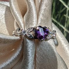 Brilliant sparkle with a lush Amethyst Cubic Zirconia heart shaped stone, this White Gold Amethyst engagement ring has a core of solid 925 Sterling Silver, making it hypoallergenic and built to last! The high-quality faceted heart stone is 6mm (0.8 carat) and has a Mohs hardness of 8-1/2. Sprinkled generously with cubic zirconia rhinestones, this lovely Amethyst ring is accented by a nature-inspired tree branch and leaf design.It would make a great promise ring or engagement ring, as well as an Purple Cubic Zirconia Jewelry For Valentine's Day, Elegant Heart Cut Amethyst Promise Ring, Heart Cut Amethyst Ring With Accent Stones, Heart Cut Amethyst Jewelry With Center Stone, Elegant Silver Amethyst Ring For Valentine's Day, Purple Cubic Zirconia Crystal Promise Ring, Purple Heart Cut Cubic Zirconia Jewelry, Heart Cut Purple Jewelry For Valentine's Day, Purple Heart Cut Jewelry For Valentine's Day