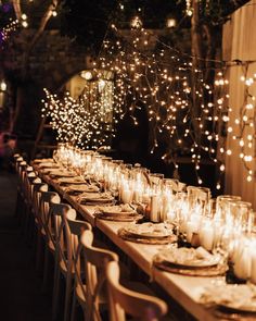 a long table is set with candles and plates for an outdoor dinner or party event