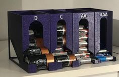 three purple boxes are stacked on top of each other with different types of batteries in them