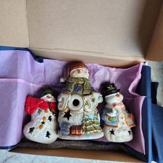 three ceramic figurines in a box on a table