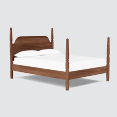 a wooden bed frame with white sheets and pillows on top of it, against a gray background