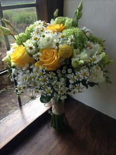 a bouquet of yellow and white flowers on a window sill