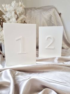 two white square numbers sitting on top of a bed next to a vase with flowers