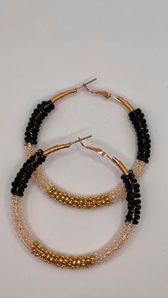 Embrace your bohemian spirit with our handcrafted Black & Gold Wire Wrapped Hoop Earrings. These one-of-a-kind earrings feature a mesmerizing swirl of black and gold seed beads meticulously wrapped around lightweight gold-tone hoops. Each bead is carefully secured by hand, creating a unique and textured design that catches the light and adds a touch of boho chic to any outfit.  The combination of black and gold exudes an air of sophistication, making these earrings perfect for both everyday wear and special occasions. Why You'll Love These Hoop Earrings: Handcrafted Artistry: Each pair is meticulously crafted with love and attention to detail. Unique Design: The wire-wrapped seed bead pattern ensures no two pairs are exactly alike. Bohemian Flair: Embrace a free-spirited aesthetic with the Wire Wrapped Beaded Hoop Earrings, Bohemian Small Hoop Earrings For Parties, Bohemian Round Hoop Earrings For Party, Adjustable Dangling Beads Hoop Earrings For Party, Adjustable Hoop Earrings With Dangling Beads For Party, Adjustable Hoop Beaded Earrings For Party, Bohemian Hoop Beaded Earrings For Party, Bohemian Beaded Hoop Earrings For Party, Bohemian Party Hoop Beaded Earrings