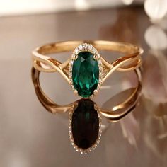 an emerald and diamond ring sitting on top of a table