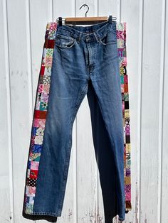 an old pair of jeans with patchwork on them hanging from a clothes hanger