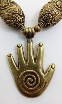 "This gorgeous necklace is comprised of all brass components including a Tibetan brass Hamsa Hand or \"Hand of Fatima\" pendant, Tibetan brass repousse beads and rare brass African pendant beads that are shaped like battle axe heads or crescents. The hamsa hand is a protective amulet, popular throughout Africa, Israel, Turkey and some Middle Eastern countries. The word hamsa means \"five\" and refers to fingers. The hamsa hand is also known as the Hand of Fatima in reference to the daughter of M Bohemian Gold Hand Cast Necklace, Spiritual Bronze Necklace With Antique Finish, Bronze Spiritual Necklace With Antique Finish, Spiritual Bronze Beaded Brass Necklaces, Unique Brass Necklaces With Round Beads, Antique Gold Brass Necklace For Rituals, Vintage Bronze Beaded Brass Necklaces, Bronze Brass Jewelry With Large Beads, Adjustable Bronze Beaded Brass Necklace