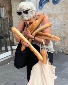 an older woman carrying breadsticks in her hands