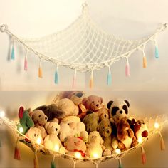 a hammock filled with lots of stuffed animals under a string light net hanging from the ceiling