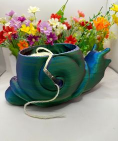 a vase with flowers in it sitting on a table next to a white cord and thread