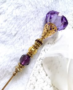 "8.1/2\" HATPIN with Large Dark PURPLE Crystal Shape and Round Faceted Crystal on Gold Finish Setting. The Large Faceted Purple Bead on Top is 7/8\"x 3/4\", in the Center a Purple Rhinestones Roundel and at the base, a Round Faceted Crystal 3/8\" diameter, all set  Gold Finish Findings.  THE DECORATED AREA IS  2.7/8\" ON THE 8.1/4 INCH HATPIN. MADE OF STAINLESS  VERY CLASSY TO WEAR, ADD IT TO YOUR COLLECTION OR OFFER AS A GIFT. OUR HATPIN SHIP WITH A METAL SAFETY END. The rod is sturdy made of 15 Gauge Brass. ------------------------------------  * Hand crafted in the U.S.A.  * Limited edition hatpins, not mass produced abroad.   * Payment must be received in 10 days.  * Dotty is now Retired and a graduate from The Maryland Institute of Art and meticulously creates these hatpins with parts Purple Gold Aesthetic, Wand Ideas, Dark Purple Crystal, Gold And Lavender, Fairy Shoes, Pretty Knives, Pretty Jewelry Necklaces, Gold And Purple, Anime Accessories