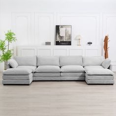 a living room with white walls and wood flooring on the floor, an l shaped sectional sofa sits in front of it