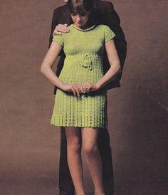 a woman standing next to a man in a green dress