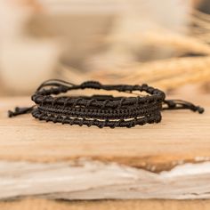 two black bracelets sitting on top of a wooden table next to some wheat stalks