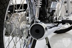 the front end of a motorcycle with chrome spokes and black exhaust pipe on it