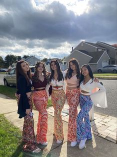 four women standing on the sidewalk with their arms around each other and one woman wearing colorful pants