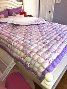 a bed with purple and white bedspread on it