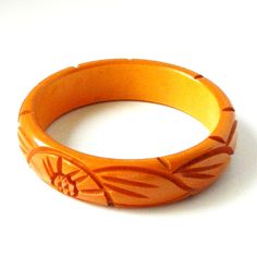 "Item: This is a lovely bakelite bangle bracelet carved with flowers and leaves on either side. It was made in the late 1930s and has a very deep yellow / orange color. It's in excellent condition, has been tested and guaranteed vintage bakelite. Be sure to check our other listings for lots more bakelite jewelry! Measurements: 3/4\" wide - 2 1/2\" inner diameter, 3\" outer diameter, 7 3/4\" inner circumference. Condition: 9.5 - Excellent Shipping: U.S shipping is $5.00 for USPS First Class Mail Vintage Bakelite Bangle Jewelry, Vintage Bakelite Bangle, Vintage Orange Bangle Bracelets, Vintage Bakelite Bracelet, Vintage Carved Orange Jewelry, Orange Carved Vintage Jewelry, Vintage Orange Carved Jewelry, Jewelry Measurements, Bakelite Jewelry