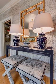 a table with two lamps on top of it next to a mirror and stools