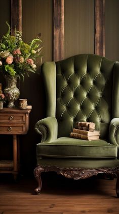 a green chair sitting in front of a wooden table with flowers on top of it