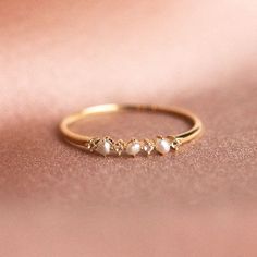 a gold ring with three pearls on the bottom and two small stones in the middle