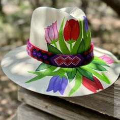 Discover the charm of our Hand Painted Hats, each adorned with a delightful tulip floral design on the front, showcasing the exquisite pintado a mano technique. These hats are beautiful expressions of artesanias mexicanas, carefully crafted and hand-painted in Mexico with an eye for detail. Made from high-quality painted straw, each piece is as unique as it is vibrant. Perfect as a regalo para mujer, especially for Dia de la Madre, these pintado a mano hats merge style with tradition. The tulip Handmade Flower Hats For Summer, Bohemian Adjustable Sun Hat For Garden Party, Adjustable Bohemian Straw Hat For Garden Party, Adjustable Bohemian Sun Hat For Garden Party, Adjustable Artisan Sun Hat For Spring, Bohemian Straw Hat For Garden Party, Adjustable Multicolor Panama Hat For Spring, Handmade Adjustable Sun Hat For Garden Party, Handmade Adjustable Straw Hat For Garden Party