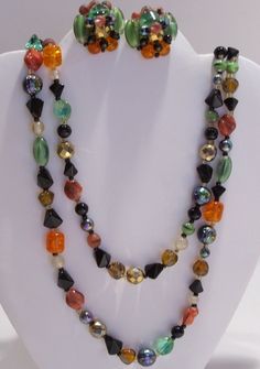 "Long Strand Necklace of Multi Color Glass Beads and Matching Clip Earrings. Glass Bead Colors Are: Orange, Green, Black, White, Gold and Blue Iridescent. Each Color Bead is a Different Shape and Type Such as : Orange-Barrel-Crackel, Green-Oval- Molded Cats Eye, White-Round-Clear, Blue Iridescent Carnival-Round, Gold-Faceted-Round, Etc. Necklace is 50\" Long and Can be Worn Long or Doubled or Tripled. Earrings Are 1\" in diameter and Stamped Made in West Germany. Colorful and Unusual! Necklace a Glass Dangle Jewelry For Parties, Party Glass Dangle Jewelry, Costume Jewelry Glass Party Jewelry, Multi-strand Glass Jewelry For Party, Colorful Glass Beads Jewelry For Party, Vintage Multicolor Jewelry With Faceted Beads, Colorful Beaded Glass Jewelry For Party, Vintage Multicolor Double Strand Jewelry, Vintage Czech Glass Jewelry With Spacer Beads