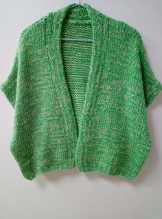 a green sweater hanging on a white wall