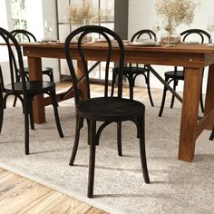 a dining room table with chairs and a rug on the floor in front of it