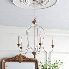 a white chandelier hanging from the ceiling in a room with a mirror and potted plant