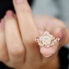 a close up of a person's hand holding a ring with an opalite