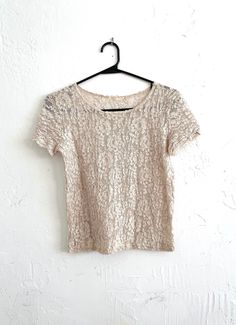 Super cute lace tee in a nice beige color with a slightly cropped, boxy fit. Top is sheer and does not include any under layer. Perfect for festival season!   Label: -- Decade: 1990s/2000s Condition: Excellent, just missing tags Materials: Most likely a polyester blend Marked Size: -- True Size: Small/Medium (more fitted on a medium) Measurements: 20 inches long 17 inches armpit to armpit 5.5 inch sleeves Sheer Lace Short Sleeve Top, Beige Tops With Lace Trim For Party, Beige Party Tops With Lace Trim, Beige Lace Top With Short Sleeves, Sheer Lace Top Short Sleeve For Spring, Spring Lace Top T-shirt With Crew Neck, Beige Short Sleeve Blouse With Lace Top, Beige Short Sleeve Lace Top Blouse, Beige Lace Top Short Sleeve Blouse