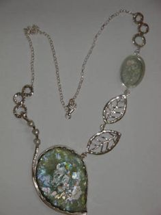 "Description: Amazing One Of A Kind 2000 Year old Roman Glass Necklace with Delicate Leaf Design In Sterling Silver. Has 3 small Pearls. Don't Wait Its Unique And We Can't Make Another Just Like It Very Elegant You Will Be In The Center Of Attention. Comes With an elegant Certificate Of Authenticity. Life Time Guaranty For Repair and Replacement (In Special Cases). Roman Glass is \"Allergic\" to water never get it wet. Metal: Silver Metal Purity: 925 Sterling Dimensions: Center Piece Size Is H- Vintage Silver Jewelry With High Luster, Vintage High Luster Silver Jewelry, Unique Silver Jewelry With High Luster, High Luster Sterling Silver Jewelry In Silver, Silver High Luster Jewelry For Anniversary, Unique High Luster Silver Jewelry, High Luster Sterling Silver Jewelry, Silver Oval Necklace With High Luster, Silver Pendant Necklace With High Luster