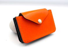 Handmade using traditional leather artisan techniques and beautiful vegetable tanned leather from Italy in a fun vibrant orange colour.  The internal pockets are made from slim and hard wearing latigo leather in a smart contrasting navy blue.  Going out out is all about the minimal now and this clever little purse can carry multiple cards and banknotes and still fit in the smallest of handbags and clutch bags.   It has a clever concertina design so it can carry many cards without being bulky.   Personalised for free!  Just add the name or initials that you would like  (up to 8 characters).  This will be positioned on the front, bottom right corner.   Please note that returns for personalised items cannot be accepted.  - handmade - personalised for free - can fit cards comfortably plus bank Orange Leather Wallets With Interior Card Slots, Orange Leather Bifold Wallet, Orange Leather Wallet With Card Slots, Orange Leather Wallet For Daily Use, Everyday Orange Leather Wallet, Orange Rectangular Wallets With Interior Card Slots, Orange Rectangular Wallet With Interior Card Slots, Orange Wallet With Card Slots For Daily Use, Orange Card Holder With Card Slots For Everyday Use