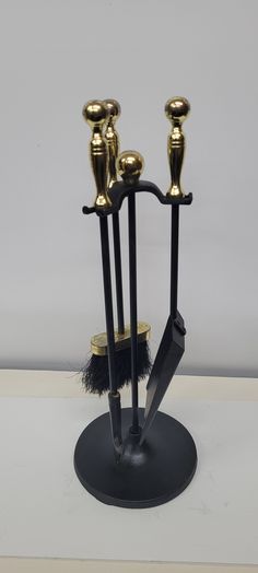 two black and gold candlesticks are on top of a stand with three small brushes