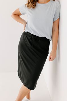 The knee-length 'Olivia' Skirt is another one of our exclusive designs. A shirt-tail hem adds a finishing touch to the classic black shade and a drawstring waist ensures maximum comfort. The 'Olivia' is fully lined and requires no layering making it the perfect option for the warmer months! Self 60% Rayon 33% Nylon 7% Spandex Lining 95% Polyester 5% Spandex Machine Wash Cold Hang to Dry Low Iron if Needed Do Not Dry Clean 2" Elastic Waist Drawstring Waist Model A Height 5'7" | Wearing Size Large Black Relaxed Fit Midi Skirt, Black Relaxed Fit Skirt With Lining, Black Relaxed Fit Skirt For Work, Black Relaxed Fit Skirt, Black Midi Skirt For Daywear, Casual Black Pencil Skirt For Fall, Black Knee-length Skirt With Elastic Waistband, Casual Black Skirt With Drawstring, Casual Black Drawstring Skirt