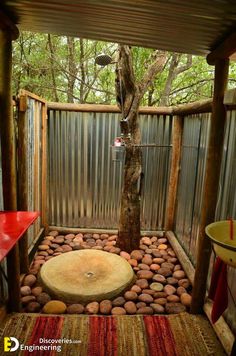 an outdoor shower with rocks in the ground and a tree growing out of it's center