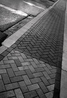 a black and white photo of a street with a stop sign on the side walk