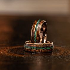 two wedding bands with green and brown wood inlays on top of each other