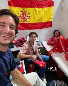 a group of people sitting around each other in a room with flags on the wall