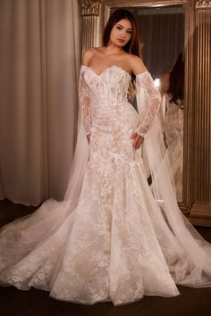 a woman in a wedding dress standing next to a mirror