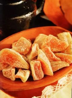 a wooden bowl filled with cut up pieces of sugary bread on top of a table