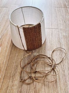 a roll of twine sitting on top of a wooden floor next to a metal container