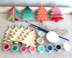 wooden christmas trees and paint are on the floor next to some other crafting supplies