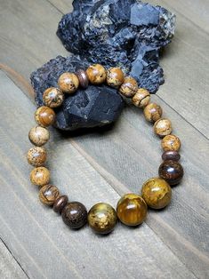 If warm earthy colors are your jam then this bracelet is for you. The backbone of this bracelet is 8mm Picture Jasper. The perfect Jasper that oozes earth energy. Up front there's three large 12mm Nellites flanked on each side by a 10mm Bronzite. Once again Nellite is the mineral vein where Pietersite and Tiger Eye collide. I apologize for repeating that description in this and other posts but it's just not a well known stone. The metal spacers are copper coated brass beads. They look like cute Brown Jasper Round Bead Bracelets, Brown Jasper Bracelets With Natural Stones, Brown Jasper Bracelets With Round Beads, Earthy Brown Beaded Bracelets With Gemstone Beads, Earthy Jasper Beaded Bracelets, Earthy Brown Bracelets With Gemstone Beads, Earthy Brown Jasper Beaded Bracelets, Earthy Brown Gemstone Beads Bracelets, Brown Stretch Bracelet With Natural Stones For Healing