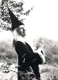 an old photo of a man dressed as wizard holding his hand up in the air