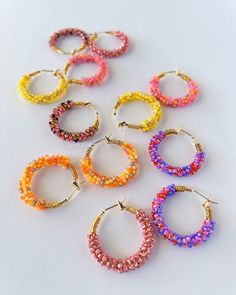 Hoop earrings adorned with vibrant seed beads create a playful and eye-catching accessory.  The wire intricately weaves through an array of colors, adding a lively touch to the classic hoop design and making these earrings a stylish and versatile statement piece. Details: ✨100% handmade with meticulous care ✨Quality 18k real gold plated hoop earrings  ✨Premium-quality glass seed beads ✨Tarnish resistant brass beading wire ✨Wired on 25mm hoop earrings  ✨Weights approximately 6g/pair  Shipping:  F Multicolor Wire Wrapped Hoop Earrings Gift, Small Hoop Earrings With Tiny Beads For Festivals, Multicolor Wire Wrapped Hoop Earrings For Gifts, Trendy Colorful Beaded Hoop Earrings For Gifts, Multicolor Small Hoop Jewelry With Spacer Beads, Multicolor Hoop Earrings With Tiny Beads, Multicolor Hoop Jewelry With Spacer Beads, Multicolor Wire Wrapped Beaded Earrings, Trendy Hoop Earrings With Tiny Beads For Gift